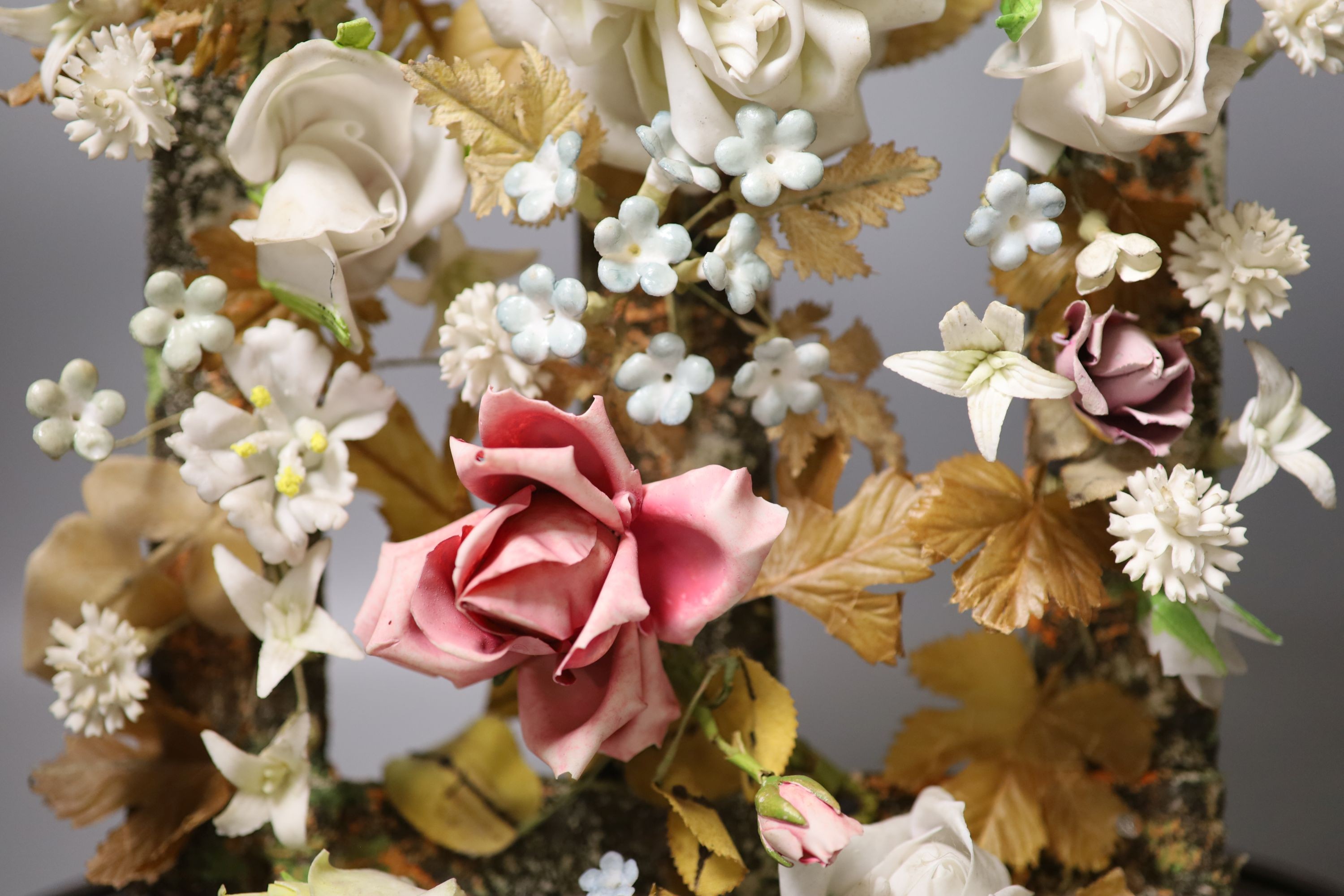 A late 19th century model of porcelain flowers under a glass dome 52cm total height